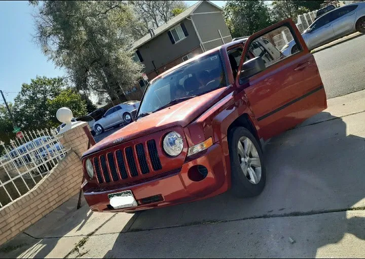 An orange Jeep Patriot at the curb after service