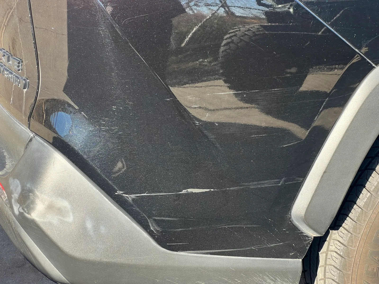 Deep scrapes and scuffs along a black car's rear quarter panel, before bodywork